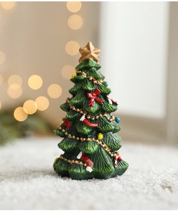 Detailed view of mini green resin Christmas tree with golden star and red ornaments