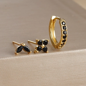 Detailed macro view of S925 silver petal stud earrings and gold hoops with black stones