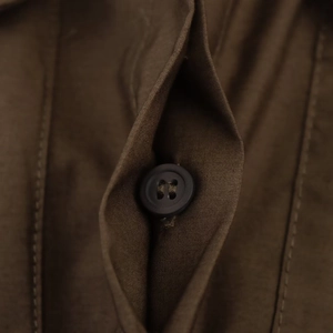 Macro shot of brown poplin shirt dress fabric detailing buttons and stitching textures