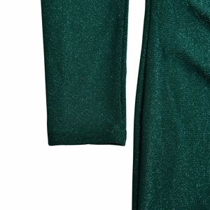 Close-up of the dark green glittery fabric texture and sleeve detail of the dress