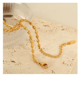 Macro detail of golden oval bead necklace with lobster clasp and extension chain