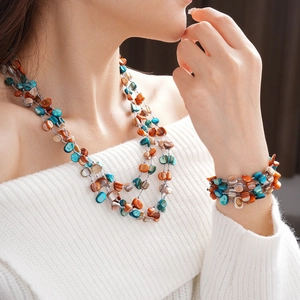 Detail of layered orange and blue irregular shell necklace and bracelet on a model