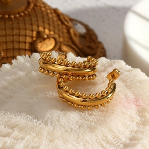 Macro detail of 18K gold plated C-shaped hoop earrings with beaded bohemian texture