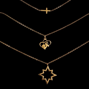 Detailed view of three gold stainless steel necklaces with cross, star, and heart pendants