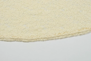 Detailed close-up of beige floral lace pattern with fine stitching on long sleeve dress