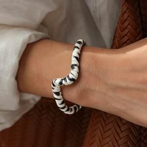 Close-up of zebra pattern wavy open bangle on wrist with neutral fashion textures