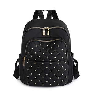 Zaino in nylon nero con trapuntatura a rombi e borchie dorate su sfondo bianco