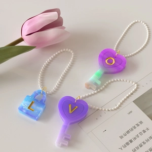 Close-up of glitter resin heart and lock keychains with gold letters and ball chains
