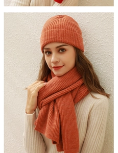 Detail eines weichen orangefarbenen Stricksets aus Mütze und Schal an einem Model