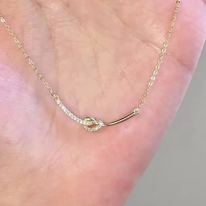 Elegant gold S925 sterling silver bow knot necklace with sparkling crystals on palm
