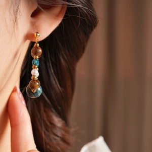 Detail shot of vintage beaded drop earring with tiger eye and pearl on female model