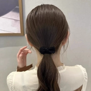 Detail view of a black bow towel hair tie styled on a high ponytail for women