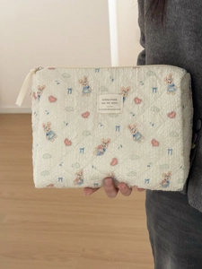 Close-up of quilted beige makeup bag with cute blue dress rabbit and heart print patterns