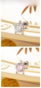 Close-up of star and flower zircon earrings in white and pink on a cream tray