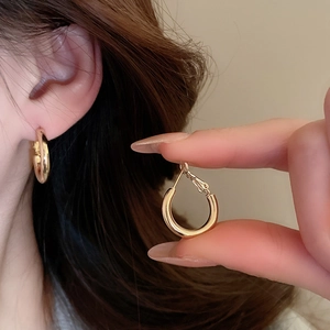 Close-up of golden oval hoop earring featuring a polished finish and secure clasp