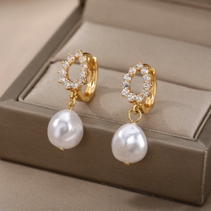 Close-up of gold geometric earrings with pavé zircons and white drop pearls