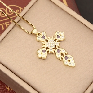 Detail of 18K gold cross pendant necklace with zircon and purple gemstones in jewelry box