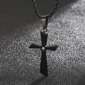Close-up of a black stainless steel cross pendant with a small sparkling gemstone inlay