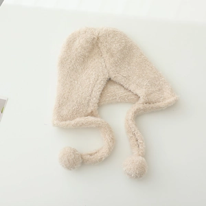 Detailansicht der beigen Plüsch-Baby-Wintermütze mit Ohrenklappen und weichen Pompons