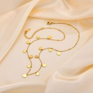Dettaglio macro della collana dorata in acciaio inossidabile con ciondoli stella e cuore