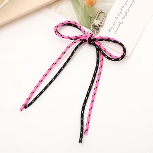 Pink and black nylon woven bow pendant with silver lobster clasp on a ceramic tray