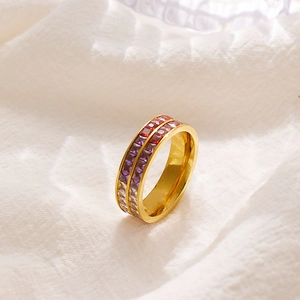 Anello dorato a doppia fila con zirconi colorati sfumati su sfondo di tessuto bianco