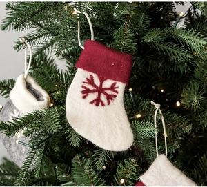 Detail of wool felt Christmas stocking with red snowflake embroidery on tree branch