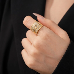 Detailed close-up of a wide gold ring with pavé zircons and a rectangular center stone
