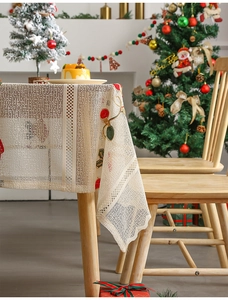 Detail of beige lace Christmas tablecloth with festive holly berry embroidery and lace texture