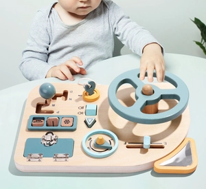 Detailed view of child's hands playing with wooden steering wheel educational busy board