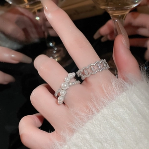 Detail of French pearl cross ring and pavé zircon geometric band on model hand