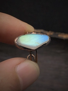 Macro view of a raw irregular labradorite stone ring with handmade copper wire wrapping