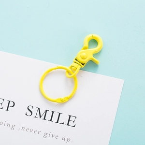 Detail of yellow spray-painted lobster clasp with swivel ring on minimalist blue background