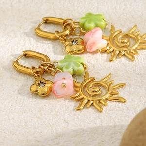 Detailed macro shot of vintage gold sun earrings with green and pink floral petal beads