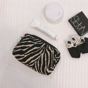 Zebra pattern knit makeup bag with top zipper closure shown in a lifestyle flat lay