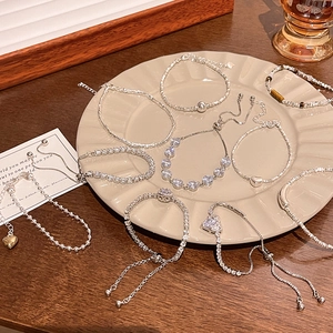 Elegant collection of silver pearl and zircon heart bracelets on a ceramic tray