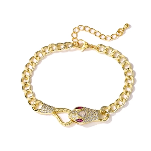 Macro detail of 18K gold-plated snake bracelet with pavé-set zircons and ruby-red accents