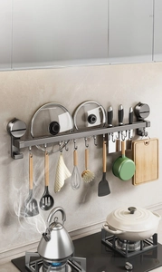 Kitchen suction cup rack with hooks holding spatulas, knives, and pot lids in a modern kitchen