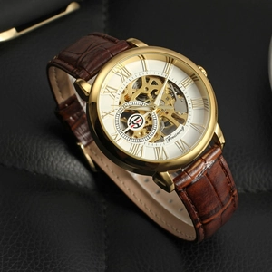 Close-up of skeleton mechanical watch with gold case and brown leather strap on leather