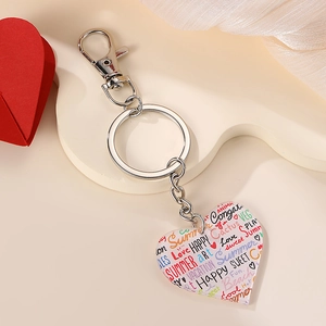 Macro shot of heart shaped acrylic keychain with colorful printed words on fabric background