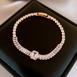 Detailed macro view of a gold-plated bracelet featuring rectangular zircon stones