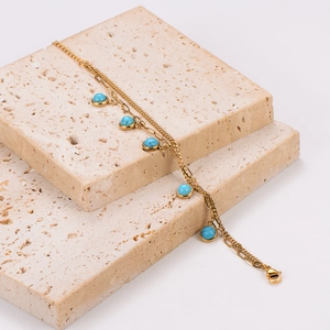 Golden stainless steel chain bracelet with five round turquoise pendants on stone props