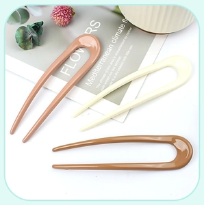 Detailed view of three minimalist U-shaped hair pins in pink, beige, and caramel resin colors