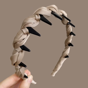 Detail of champagne silk braided headband featuring integrated black plastic hair clips
