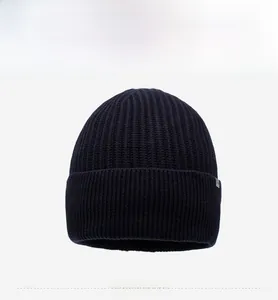 Detail of navy blue ribbed knit beanie featuring folded cuff and a small metal logo tag