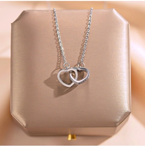 Macro shot of interlocking double heart pendant with cubic zirconia on a gold box