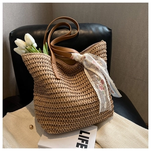 Detail of woven straw bucket tote with brown handles and white lace floral scarf