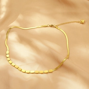 Gold double layer necklace with square charms and heart pendant on silk background