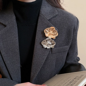 Detail view of gold and silver orchid flower brooches pinned on a dark grey suit lapel
