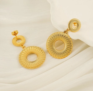 Close-up of golden double-hoop earrings with spiral woven texture on white silk fabric